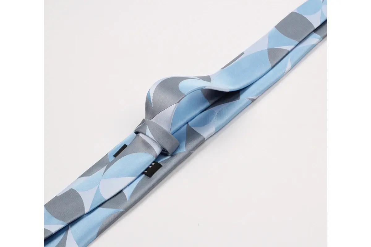 Light blue geometric tie showing a raised fold, narrow tail and finished edges.