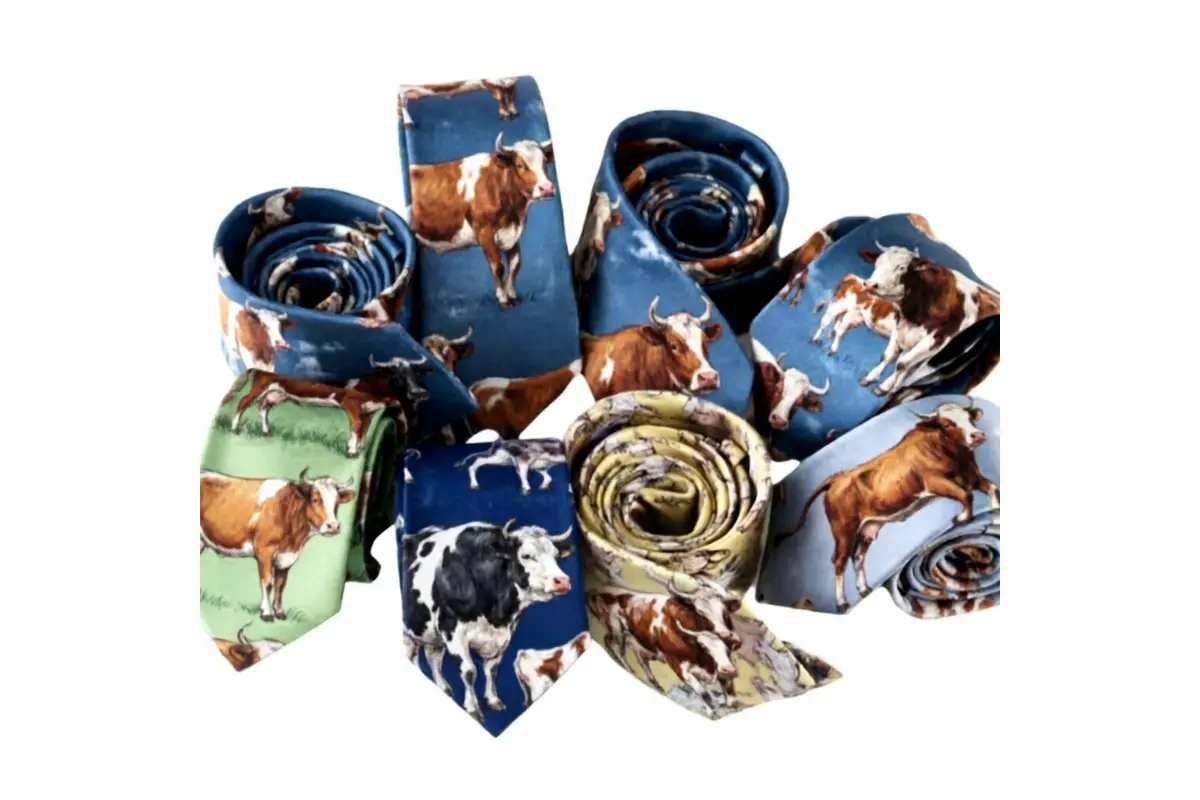 Assorted rolled ties with large colorful cattle pictures and scenic backgrounds.