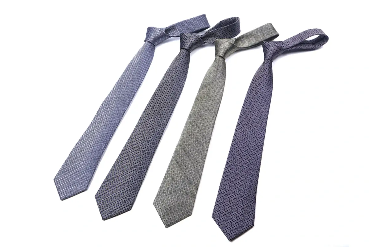 Four knotted ties in gray, blue and muted green showing their blade profiles.