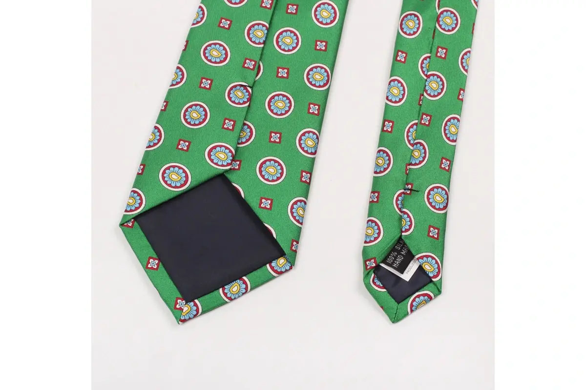 Green patterned tie reverse with circular emblems, keeper loop and dark tipping.