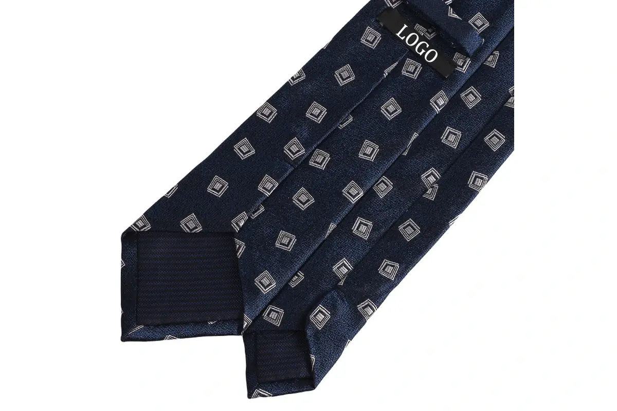 Navy tie reverse with repeated square motifs, a sample label and dark tipping.