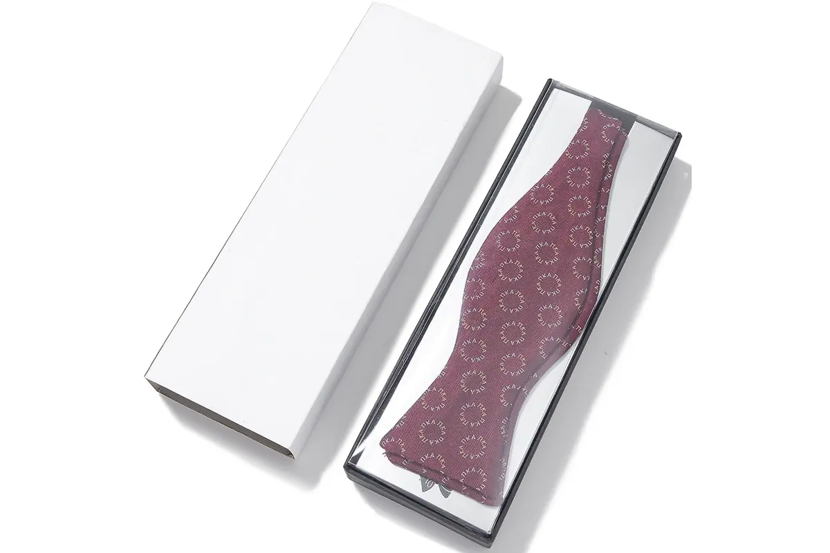 Burgundy patterned tie inside an open white rectangular box.