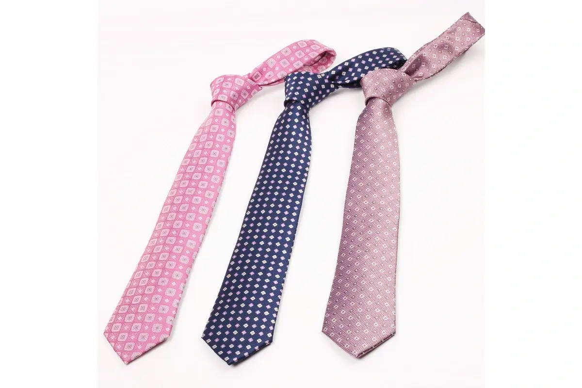 Three pink and navy patterned ties laid out with knots and tapered blades.