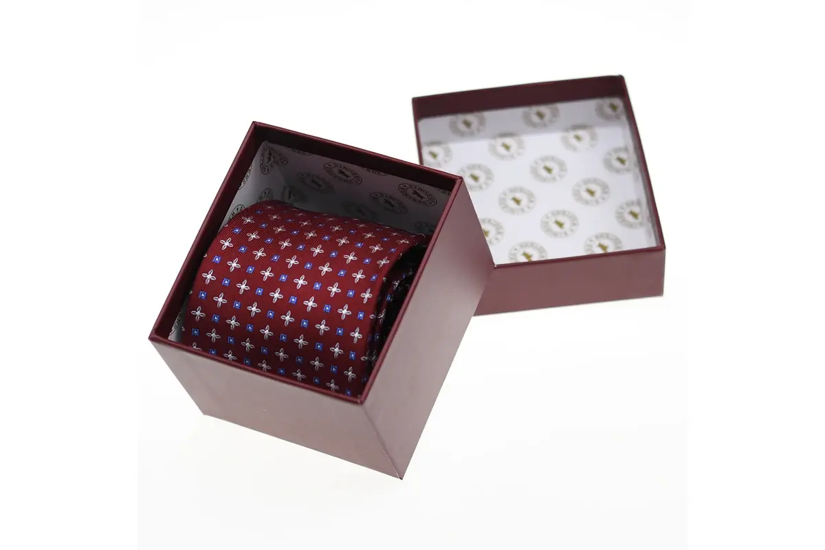 A burgundy patterned tie arranged inside an open presentation box.