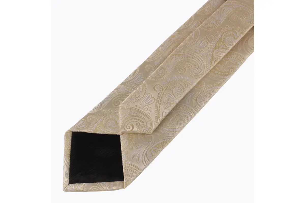 Reverse of a beige paisley tie showing the center seam and dark folded tip.