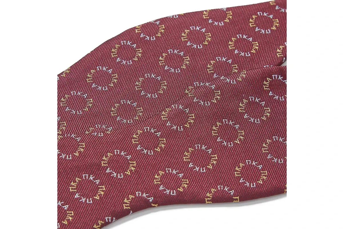 Close view of burgundy tie fabric with evenly spaced circular motifs.