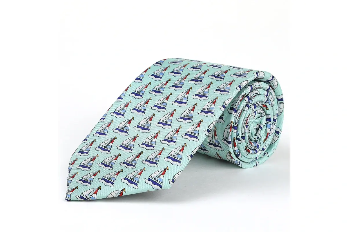 Rolled light blue tie with a repeated multicolor sailboat pattern.
