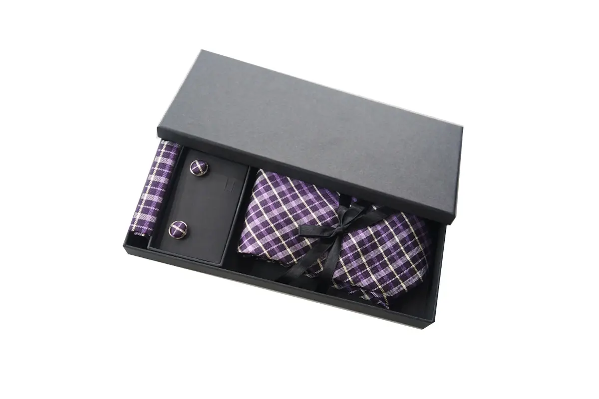Black box containing a purple plaid tie, matching bow tie and cufflinks.