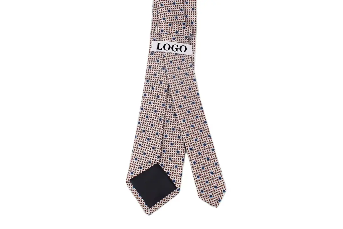 A beige patterned tie with a white sample label and dark folded tip.