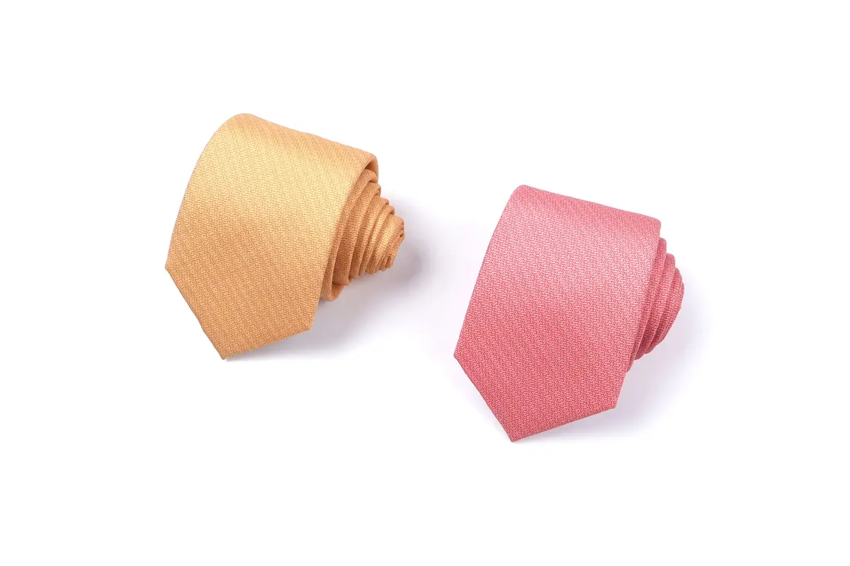 Two rolled solid-color ties in yellow and pink.