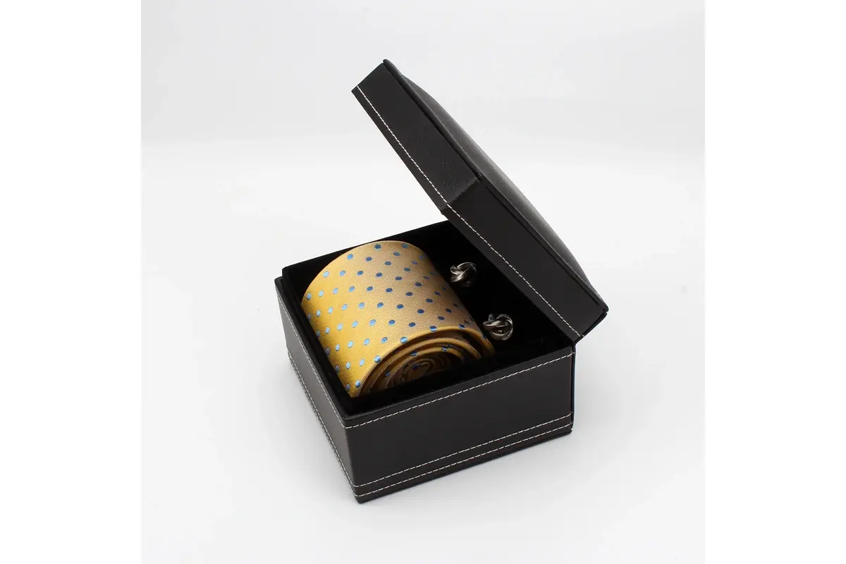 Open black box containing a yellow patterned tie and pair of cufflinks.