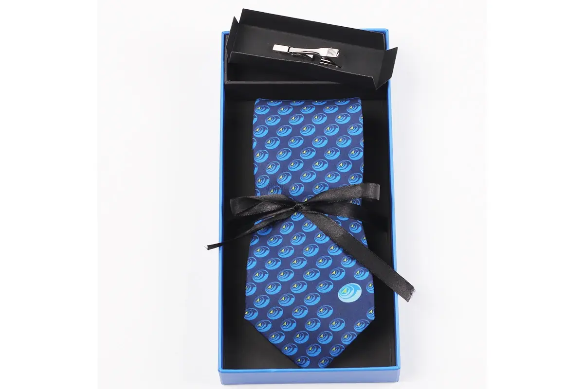 Blue patterned tie secured with a black ribbon inside an open presentation box.