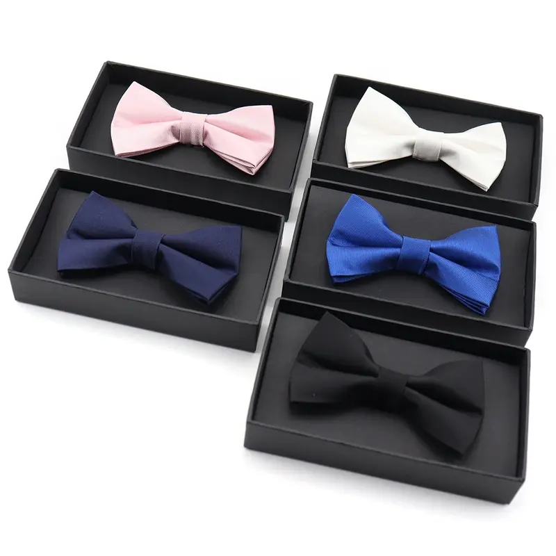 Five black boxes holding bow ties in pink, white, navy, blue and black.